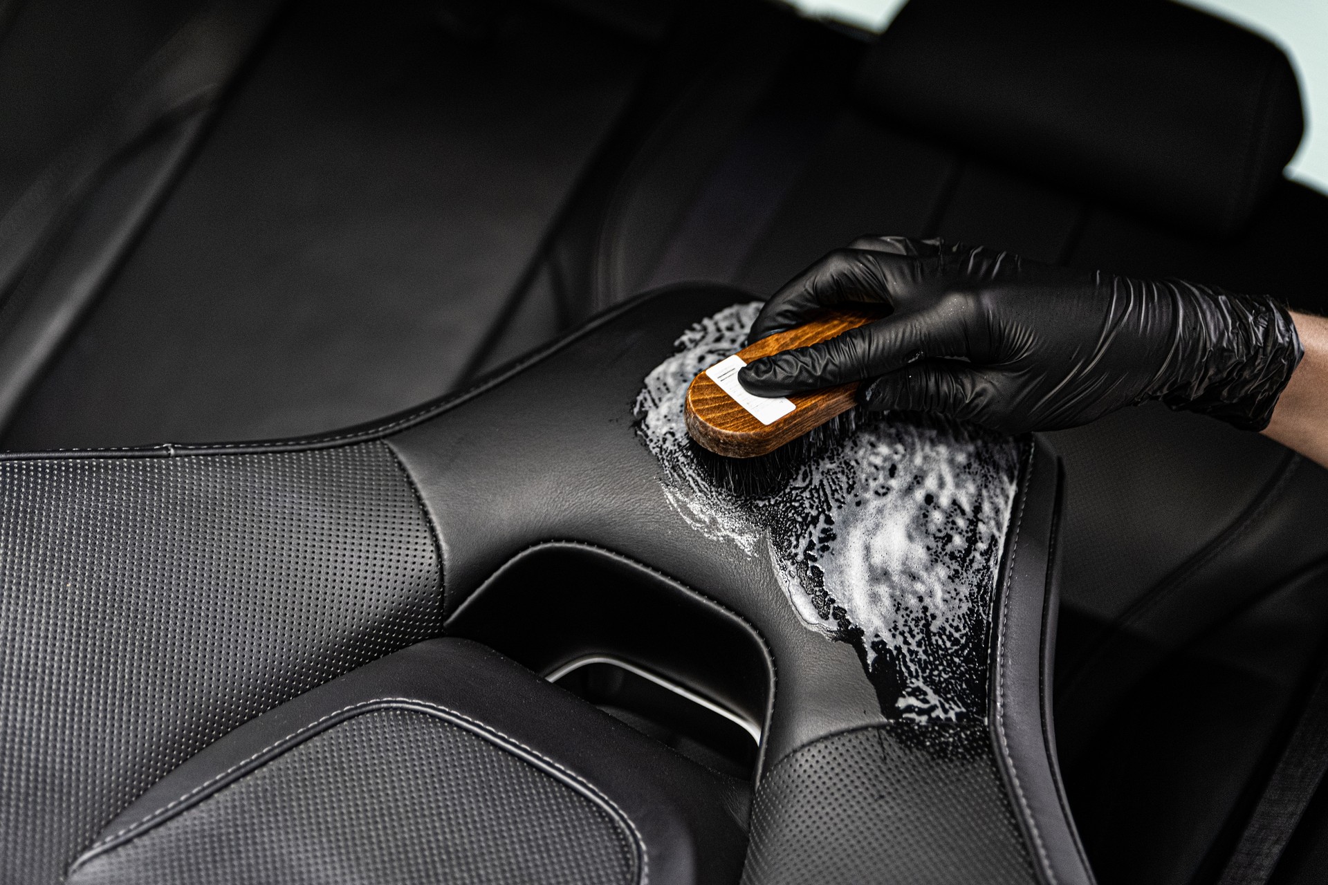 Man in rubber gloves cleaning leather car seat