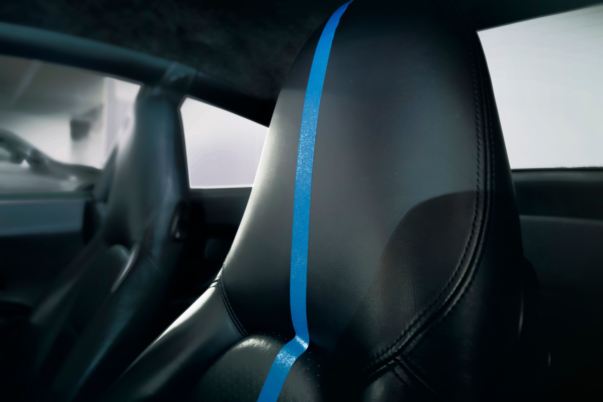Closeup View of a Luxury Car Seat During Cleaning Service With Black Leather and Blue Tape