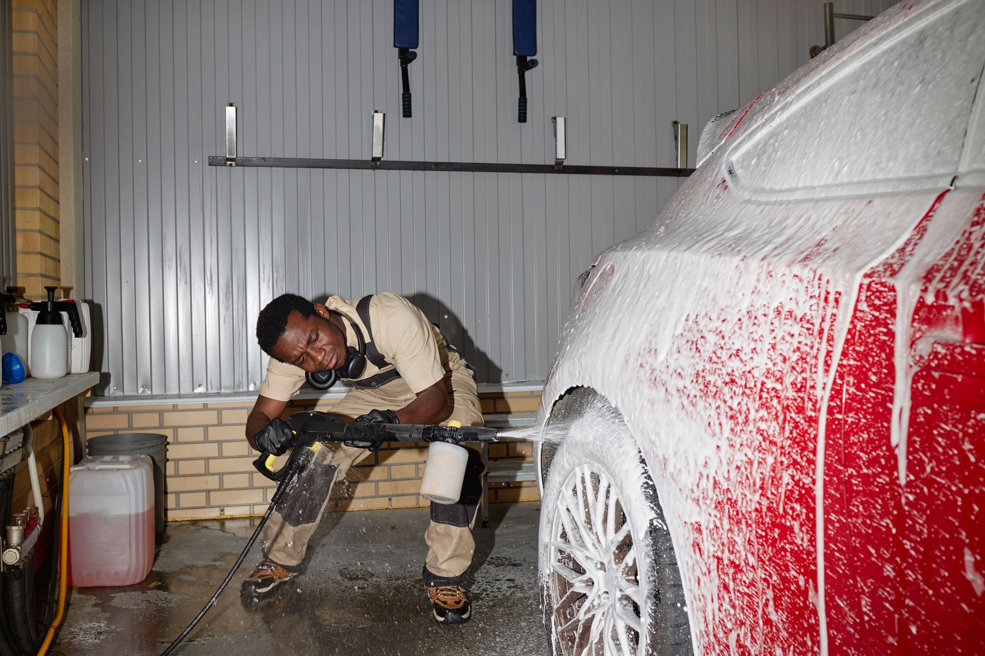 Young Adult Black Man Power Washing Red Car Wheel during Detailed Cleaning