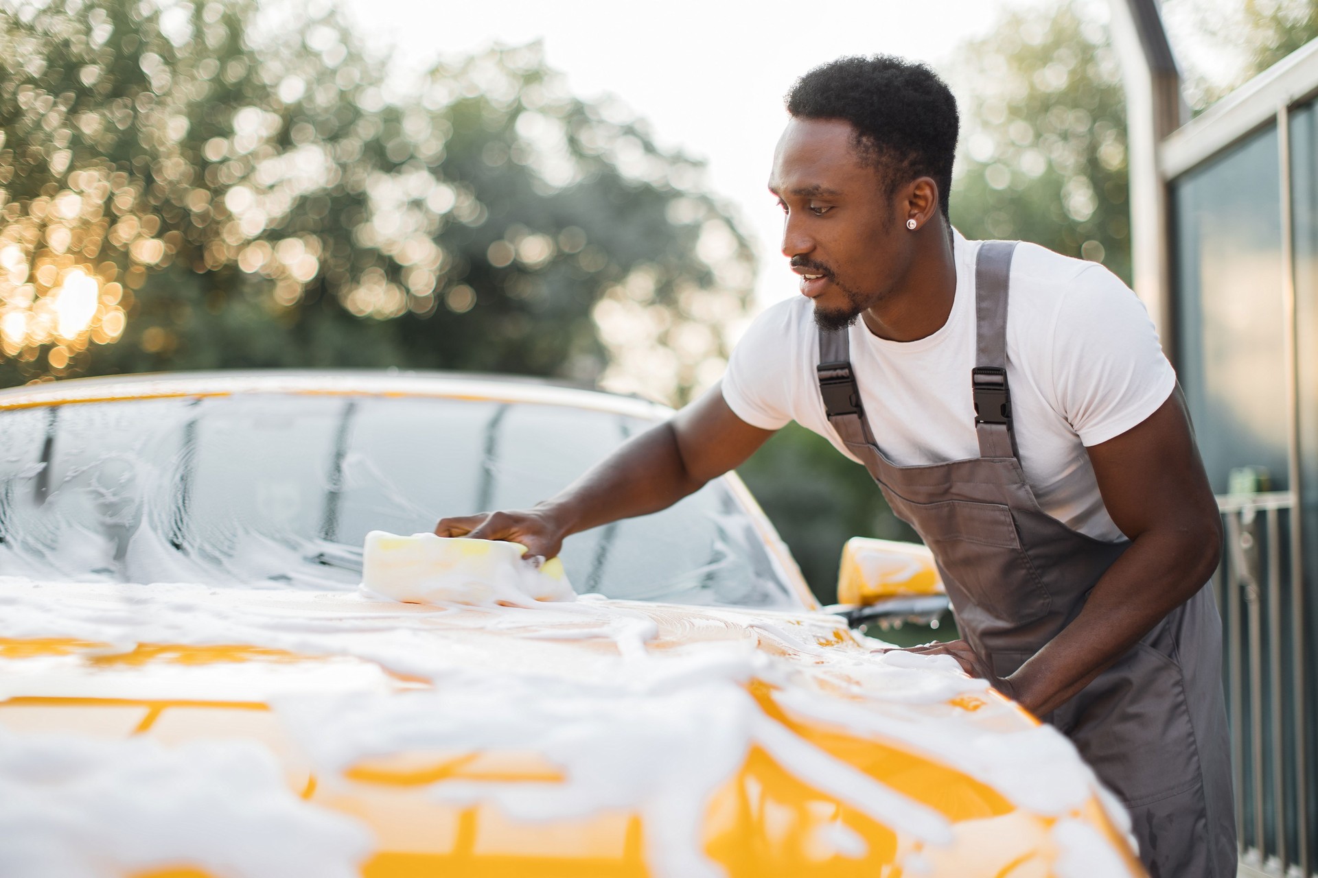 Young attractive African man washing his modern luxury car